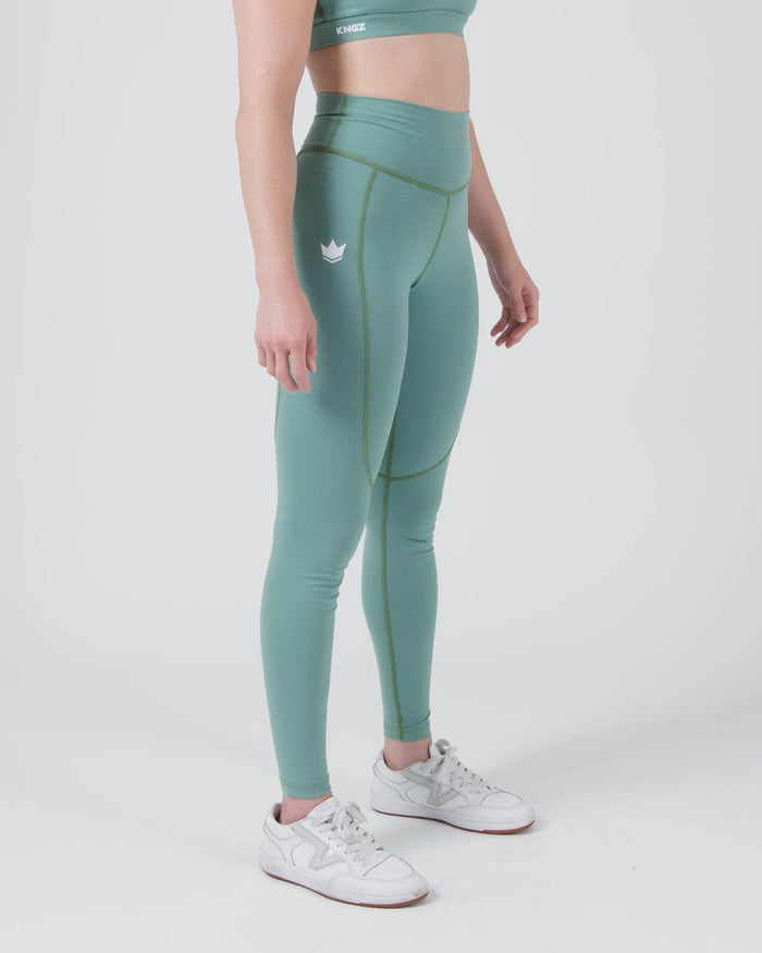 Kingz Kore Women's Grappling Spats Green - Full Body Left Side Profile Female Athlete Sage Teal Green Small White Crown Logo Left Thigh Side Seam Detail High-Waist Compression Fit Women's No-Gi BJJ Spats Kore Collection [color:Sage Green]