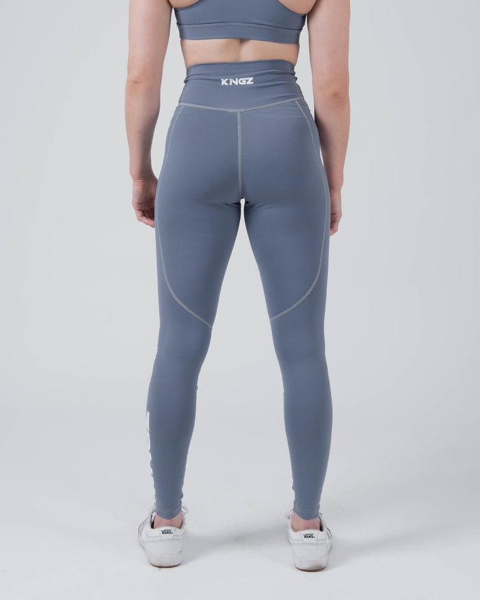 Kingz Kore Women's Grappling Spats Smoke Blue - Full Body Back View Female Athlete Slate Smoke Blue KINGZ White Text Back Waistband Rear V-Seam Seam Detail Full-Length Compression Fit Women's No-Gi BJJ Spats Kore Collection [color:Steel Blue]