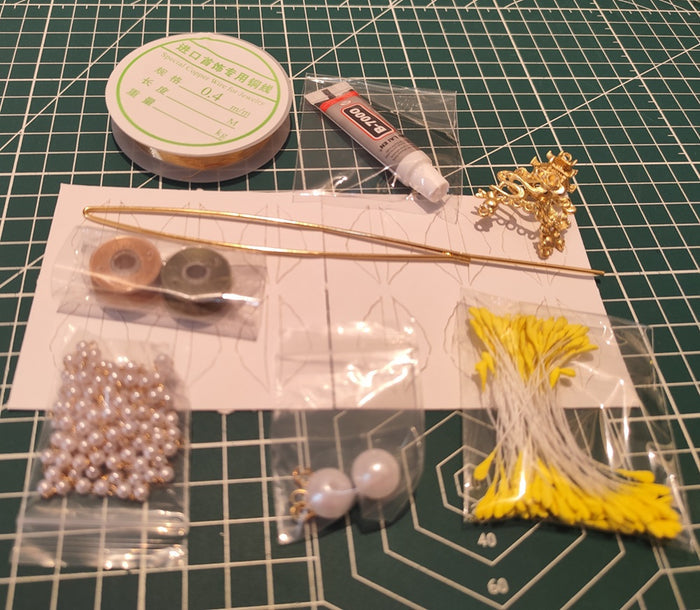 A complete DIY craft kit for making a traditional Chinese-style hairpin, showing all materials laid out, including a hairpin base, gold wire, pearls, glue, and yellow fabric flower petals.