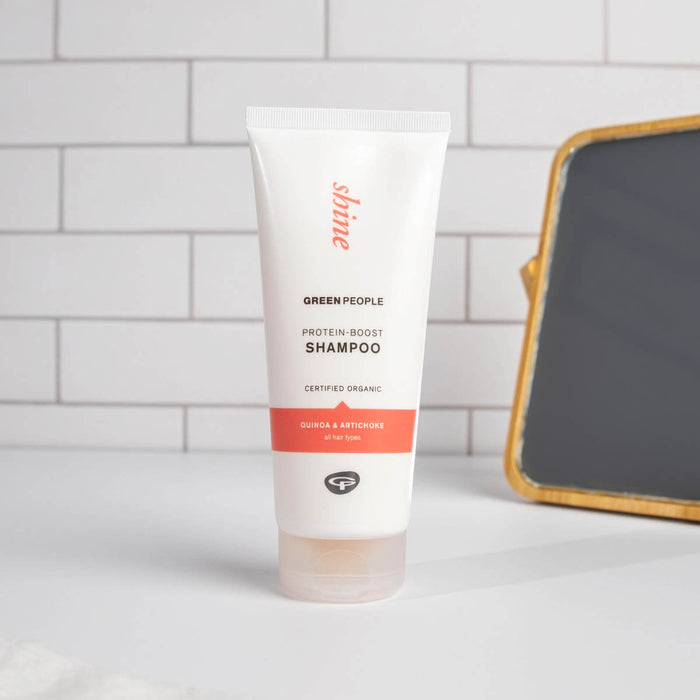 Protein-Boost Shampoo on a white bathroom vanity with tile background and small mirror stand.