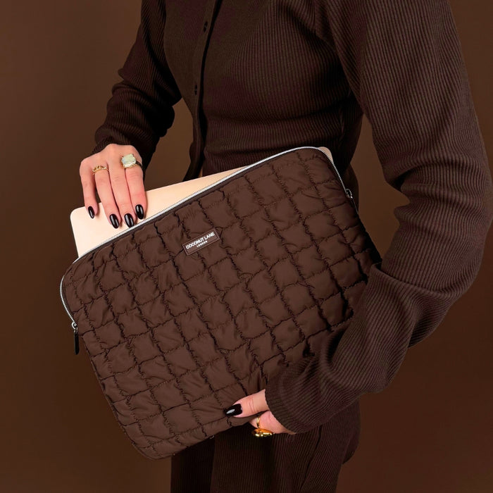 Coconut Lane quilted chocolate brown laptop sleeve held by a person in brown, with a laptop partially inside.