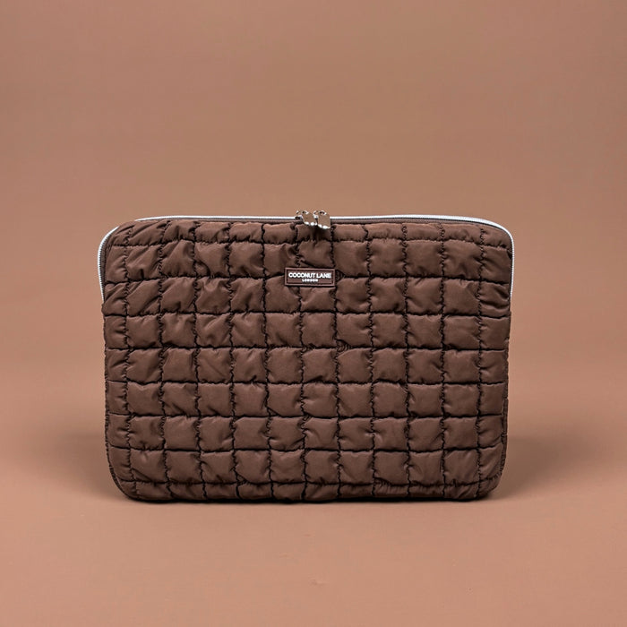Quilted chocolate brown laptop sleeve with zipper and Coconut Lane logo, shown on a brown background.