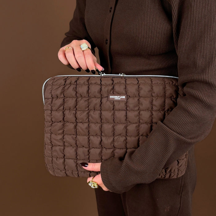 Quilted chocolate brown laptop sleeve held by a person in a ribbed brown outfit, set against a matching brown background.
