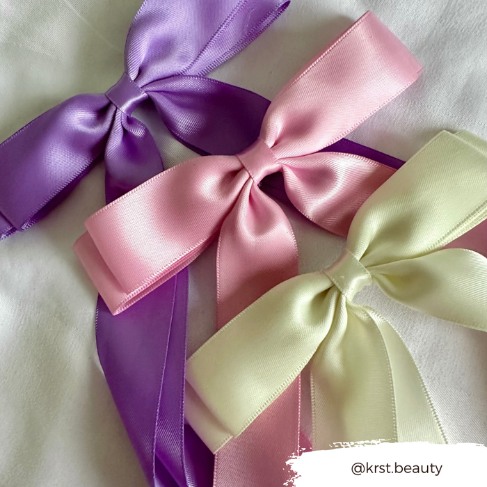Lavender, pink, and pale yellow satin ribbon bow clips on a white surface. Hyacinth Purple by Coconut Lane.