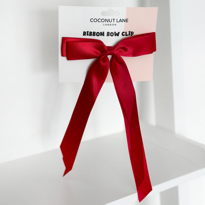 Rose red ribbon bow hair clip displayed on white Coconut Lane branded packaging.