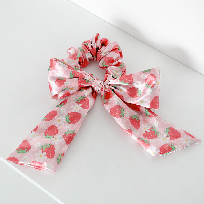 Satin bow scrunchie in pink with a red strawberry print and green leaves, from Coconut Lane.