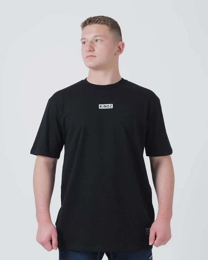 Kingz Slant Bar Tee Black - Front View Male Model KINGZ Text Center Chest Plain Black Short Sleeve T-Shirt Casual Fit BJJ Training Apparel [color:Black]