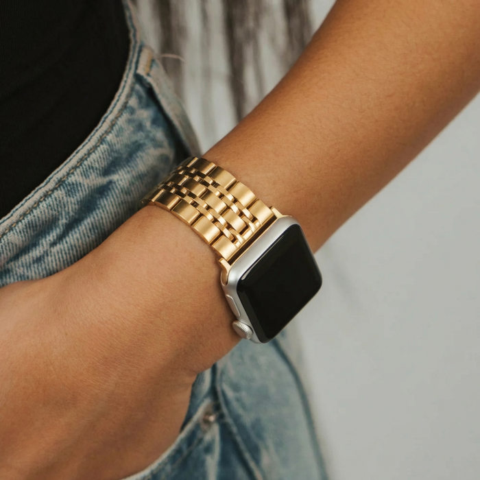 Gold Coconut Lane stainless steel Apple Watch strap worn with blue jeans and a black top.