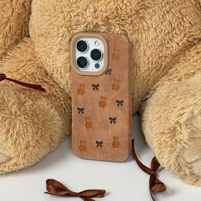 Suedette phone case with bear and bow pattern, leaning against a large teddy bear with brown ribbons.