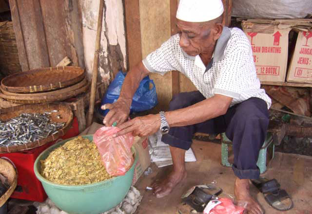 Man packaging crushed leaves in a small workshop setting