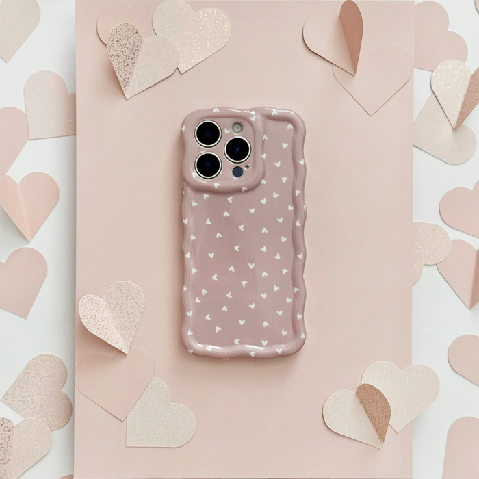 Wavy phone case with pink heart pattern on a chai background, shown with scattered paper hearts on a pink surface.