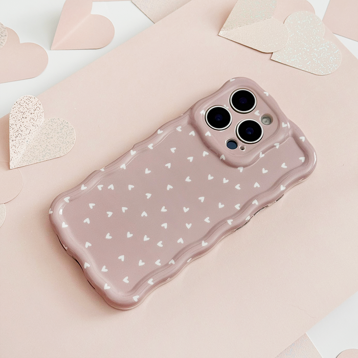Pink wavy-edge phone case with white hearts and pink glitter heart cutouts.