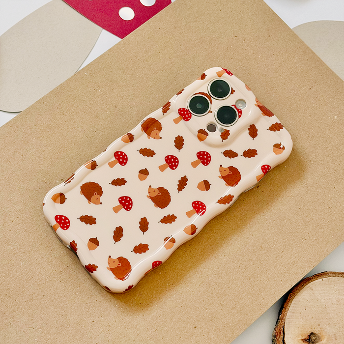 Coconut Lane phone case with beige wavy pattern, hedgehogs, mushrooms, acorns, and leaves on a brown background.