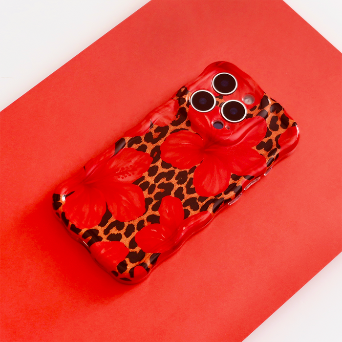 Coconut Lane wavy phone case with leopard and hibiscus pattern on a red background.