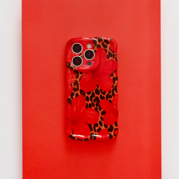 Wavy phone case with leopard and hibiscus pattern on a bright red background.