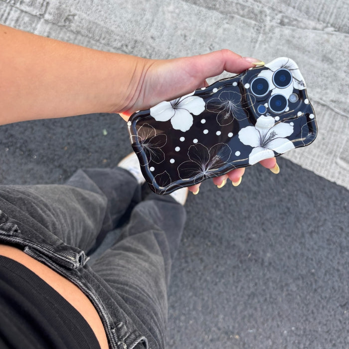 Coconut Lane Mono Flora wavy phone case held by person in gray jeans on a street.