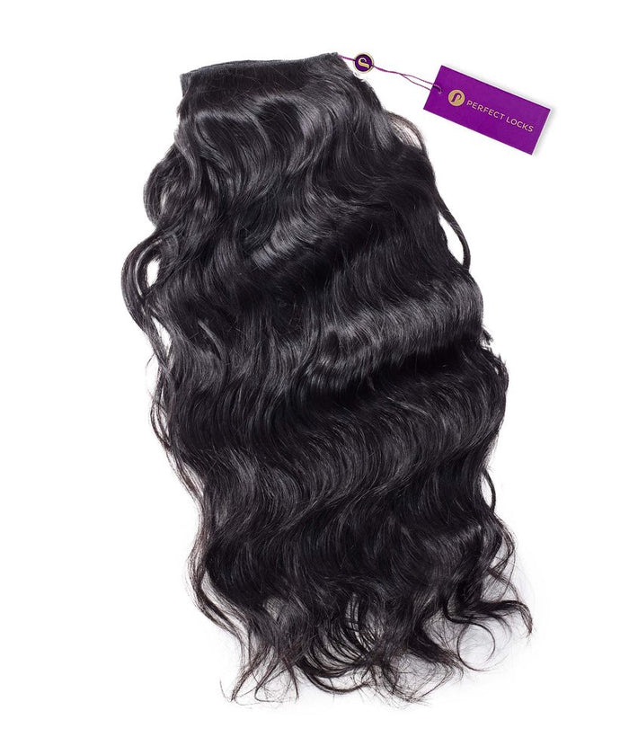 A bundle of Wavy Virgin Hand-Tied Weft by Perfect Locks in Natural Black , with shiny loose waves and a purple tag.